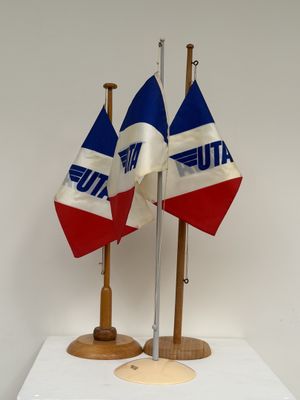 trois drapeaux posés sur un support posé sur une table