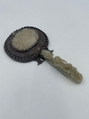 a close up of a small mirror with a handle on a white surface