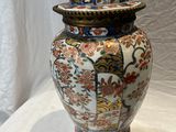 un vase posé sur une table, surmonté d'un chapeau