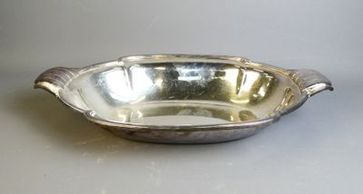 un plat ancien en argent avec un manche incurvé, posé sur une table