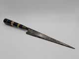 a close up of a knife on a white surface with a gray background