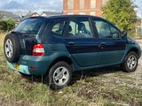 a small blue car parked in a field with a building in the background