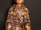 an image of a statue of a man sitting on a wooden floor next to an apple