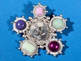 an image of a brooch with a picture of a woman surrounded by gems