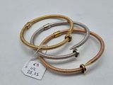 three different colored metal bracelets on a white surface