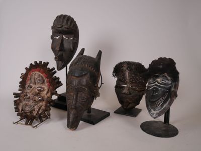 plusieurs masques africains posés sur des socles, sur une surface blanche