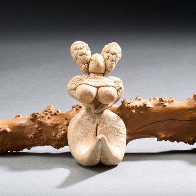 une petite figurine représentant une femme assise sur une branche