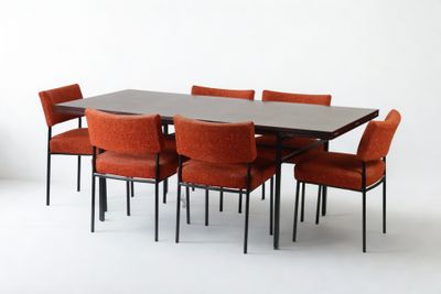une table entourée de six chaises, avec un vase posé dessus
