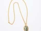 un collier en or avec un pendentif en pierre verte, monté sur une chaîne en or
