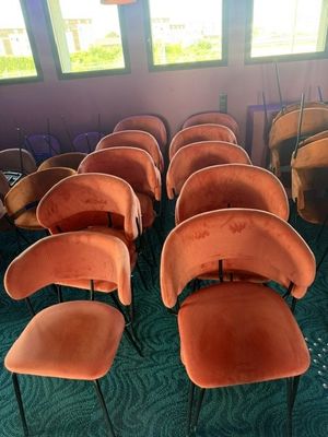 des rangées de chaises orange dans une pièce recouverte d'une moquette verte