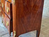 a wooden chest of drawers with a marble top on a brick floor