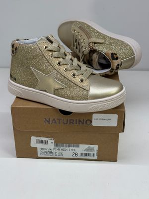 des baskets montantes dorées à paillettes, avec des lacets, posées sur une boîte en carton
