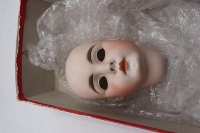 une poupée dans une boîte, enveloppée dans du film plastique