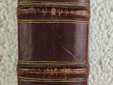 an old book with a brown cover sitting on top of a table