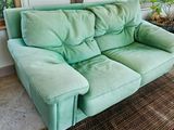 a green couch sitting in a living room next to a window