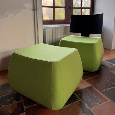 two green stools sitting next to each other on a brick floor