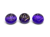 three purple marbles with gold designs on them on a white surface