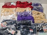 beaucoup de t-shirts de différentes couleurs posés sur une table blanche