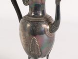 a silver tea pot with a black handle on a stand