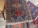 several rugs are laid out on the floor next to a chair