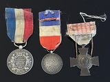 trois médailles et une croix sont disposées sur un fond noir