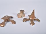 three pieces of metal on a white surface with a light in the background