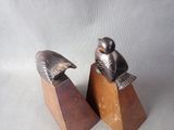 pair of metal seagulls sitting on wooden blocks on a white background