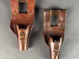 two brown leather holsters on a gray surface