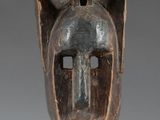 an image of a wooden mask on a stand on a white surface