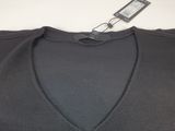 a close up of a black v neck sweater with a tag on it