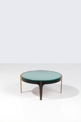 une table basse ronde en verre avec des pieds en laiton et un plateau en verre