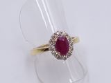 a close up of a ring with a red stone surrounded by diamonds