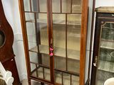 a cabinet with glass doors in the corner of a room