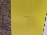 a yellow piece of paper on the ground next to a black piece of paper