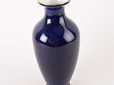 a blue vase with a gold rim sitting on a white surface