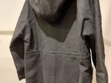 grey hooded coat hanging on a hanger in a white room