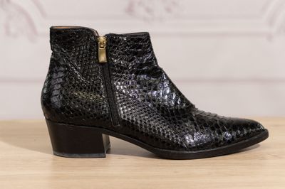 the black ankle boots are on a wooden table