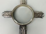 un objet en forme de croix argentée sur une surface blanche