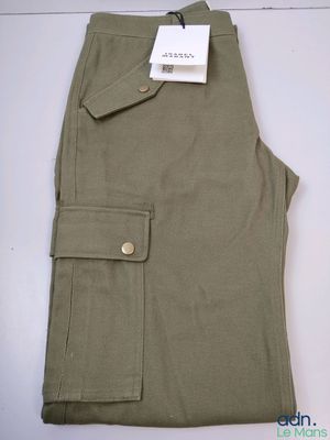 un gros plan sur un pantalon kaki posé sur une surface blanche