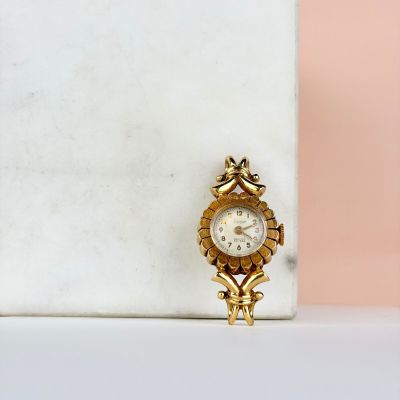 un gros plan d'une petite horloge en or posée sur un bloc de marbre