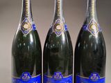 trois bouteilles de champagne sont alignées sur une table