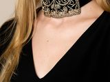 the woman is wearing a black top and a gold choker