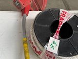 a spool of wire on a table next to a measuring tape