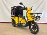 a yellow scooter that is parked in front of a white wall