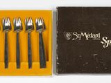 four forks and a knife in a box on a white surface