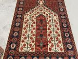 un tapis rouge et bleu posé sur un sol blanc, à côté d'une chaise