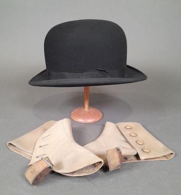 un chapeau noir posé sur un pied de mannequin et une paire de gants en cuir