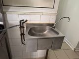 a stainless steel sink in the corner of a bathroom