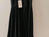 the black dress is hanging on a hanger on the wall