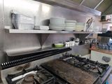 a stove top in a commercial kitchen with many dishes on it